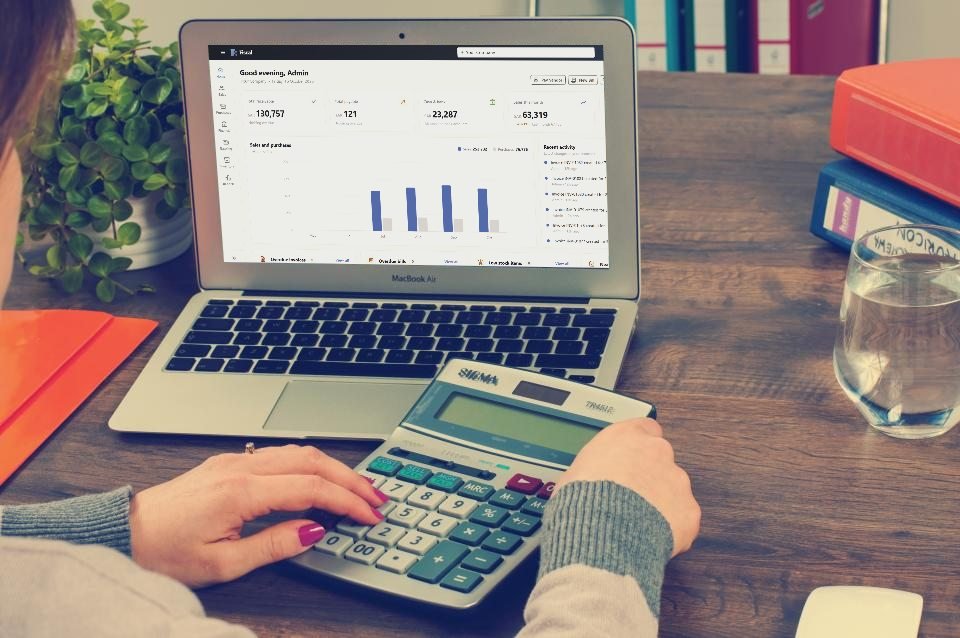 An accountant with a calculator, working in Fiscal on a laptop